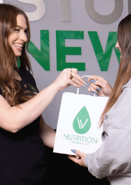 A woman holding a bag with a woman smiling after receiving vitamin injection.