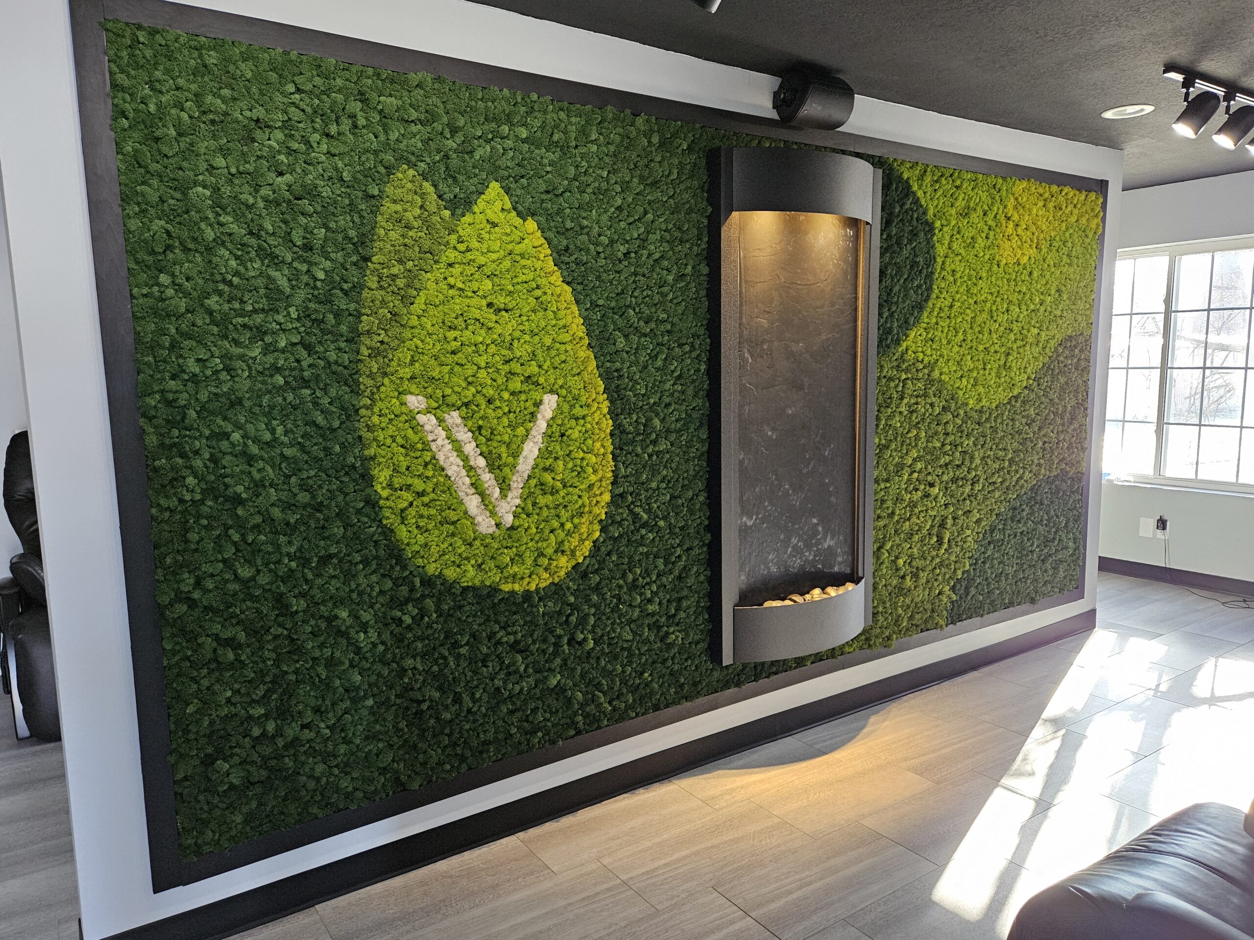 A room with a wall covered in moss, a water fountain, and vitamin injection services.