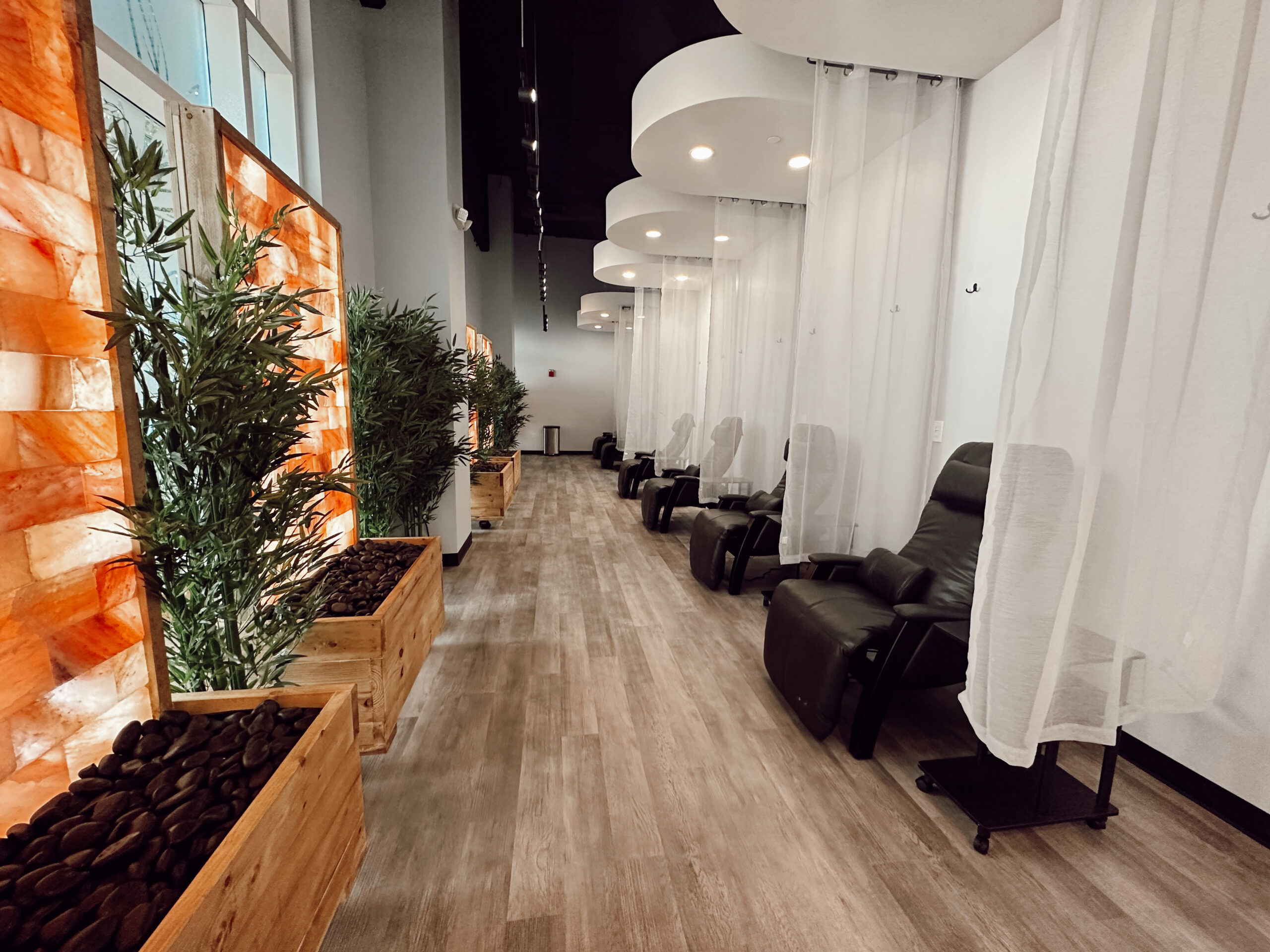 A row of chairs in a room with plants and curtains for IV therapy.